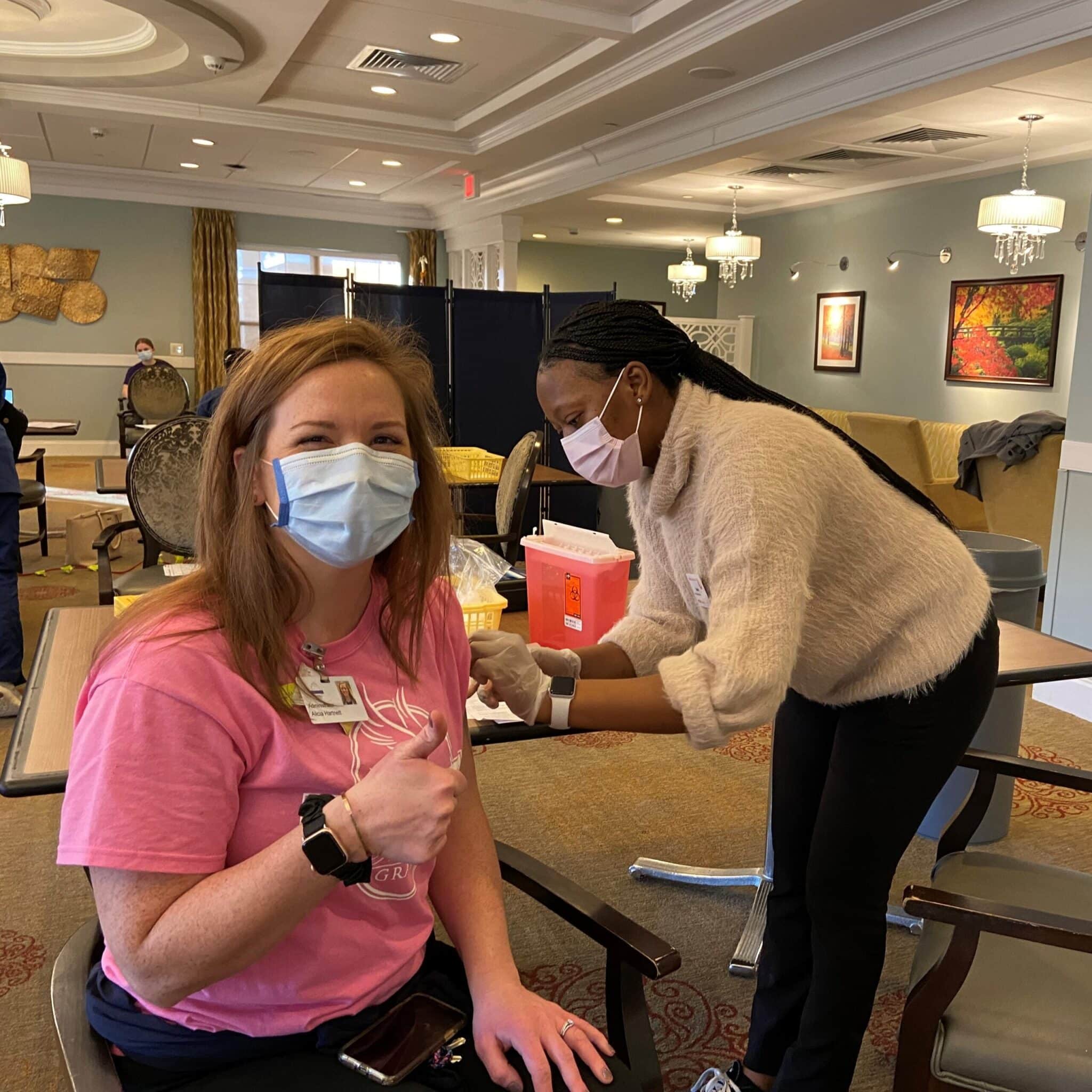 Director of Health Care Center and Assisted Living sitting in a chair giving the thumbs up as she's about to get her COVID-19 vaccine.