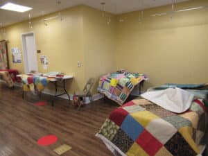 Various handmade quilts laying on tables for display. 