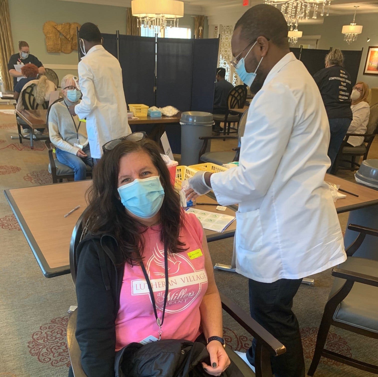 Female team member sitting in chair about to get her band-aid after her COVID-19 vaccination.