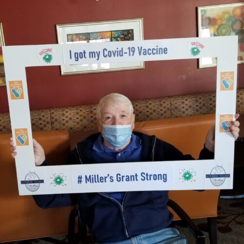 An independent living resident of LVMG holding an I Got My COVID-19 Vaccine selfie frame in front of him.