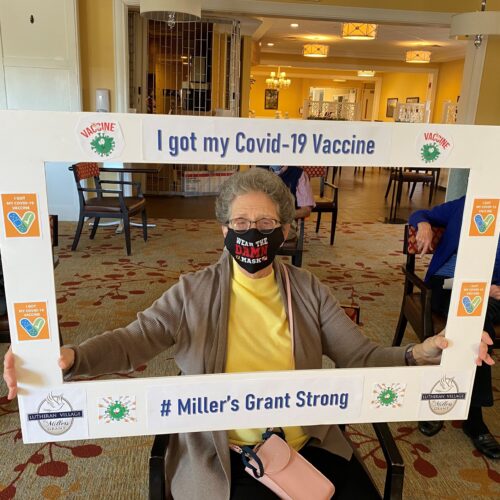 An independent living resident of LVMG holding an I Got My COVID-19 Vaccine selfie frame in front of her.
