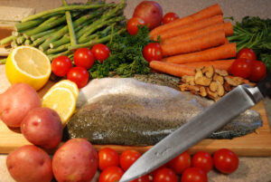 Fish meal being prepared on cutting board with natural ingredients.