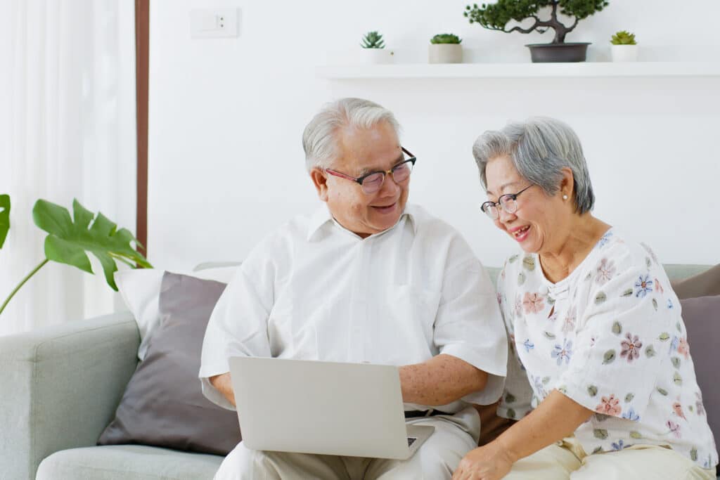 Senior Asian couple researching senior living options on a computer.