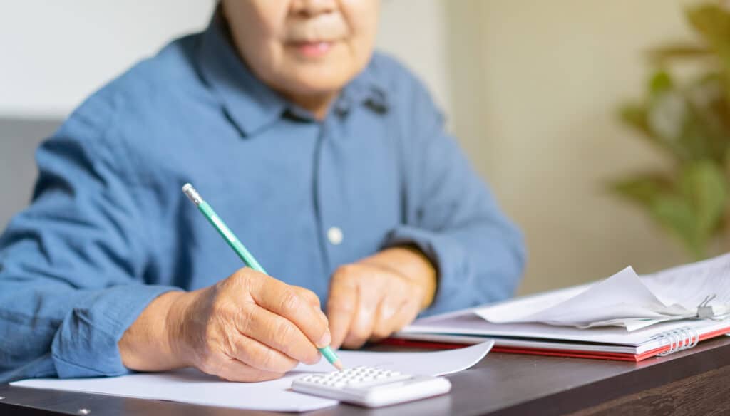 A senior doing calculations at a desk to determine the funding of senior living expenses..