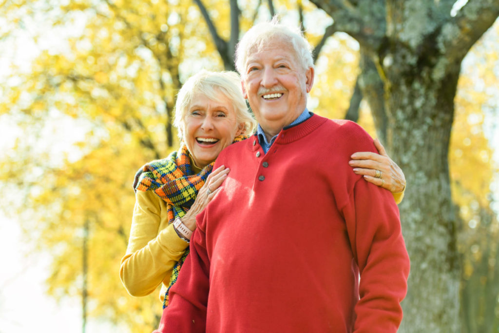 A happy senior couple enjoying the outdoors of their senior living community after deciding nursing homes were not the right decision for them.