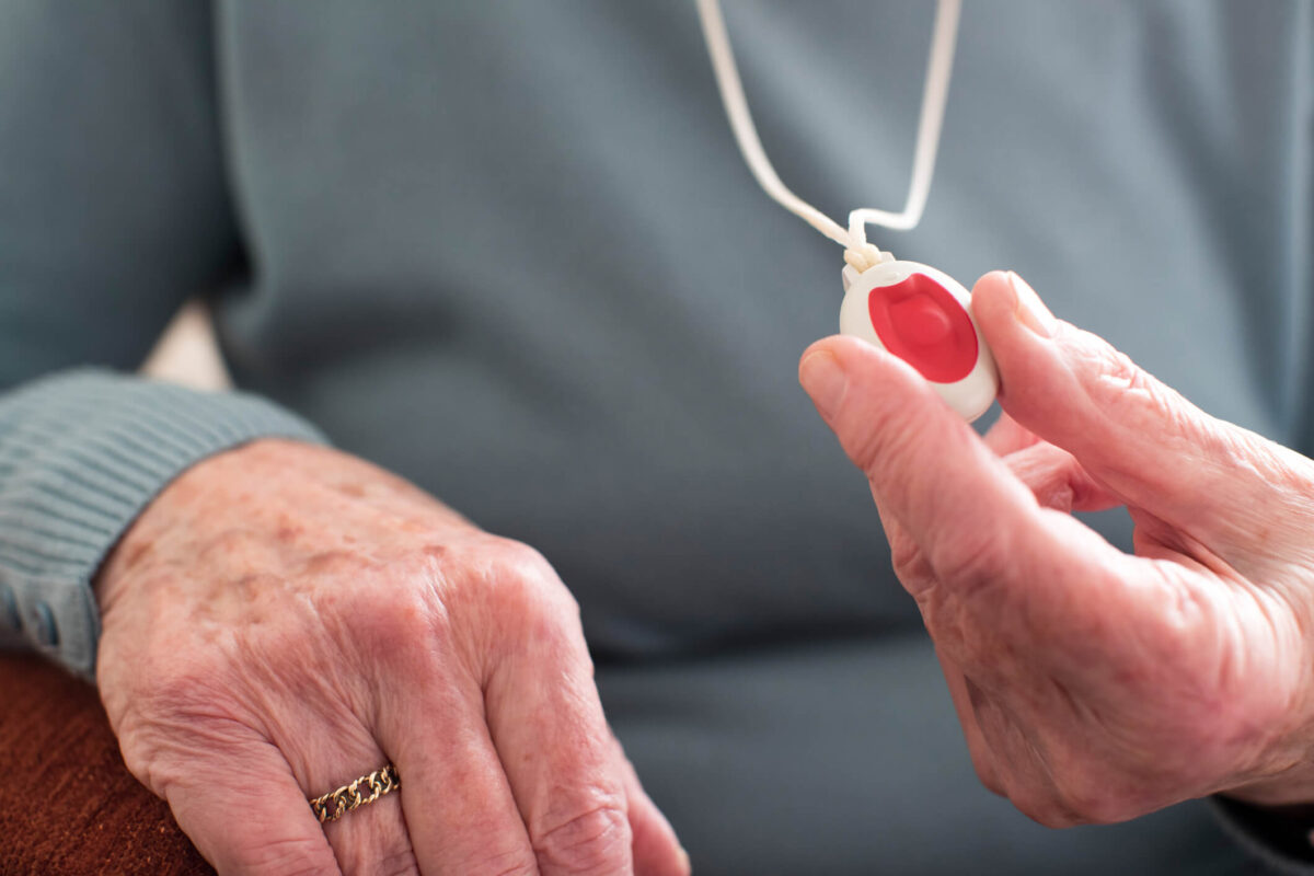 Representing personal safety for seniors, a senior woman holds her medical alert pendant.