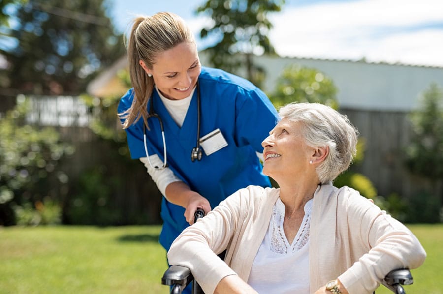 Nurse outside with an assisted living resident on a nice day.